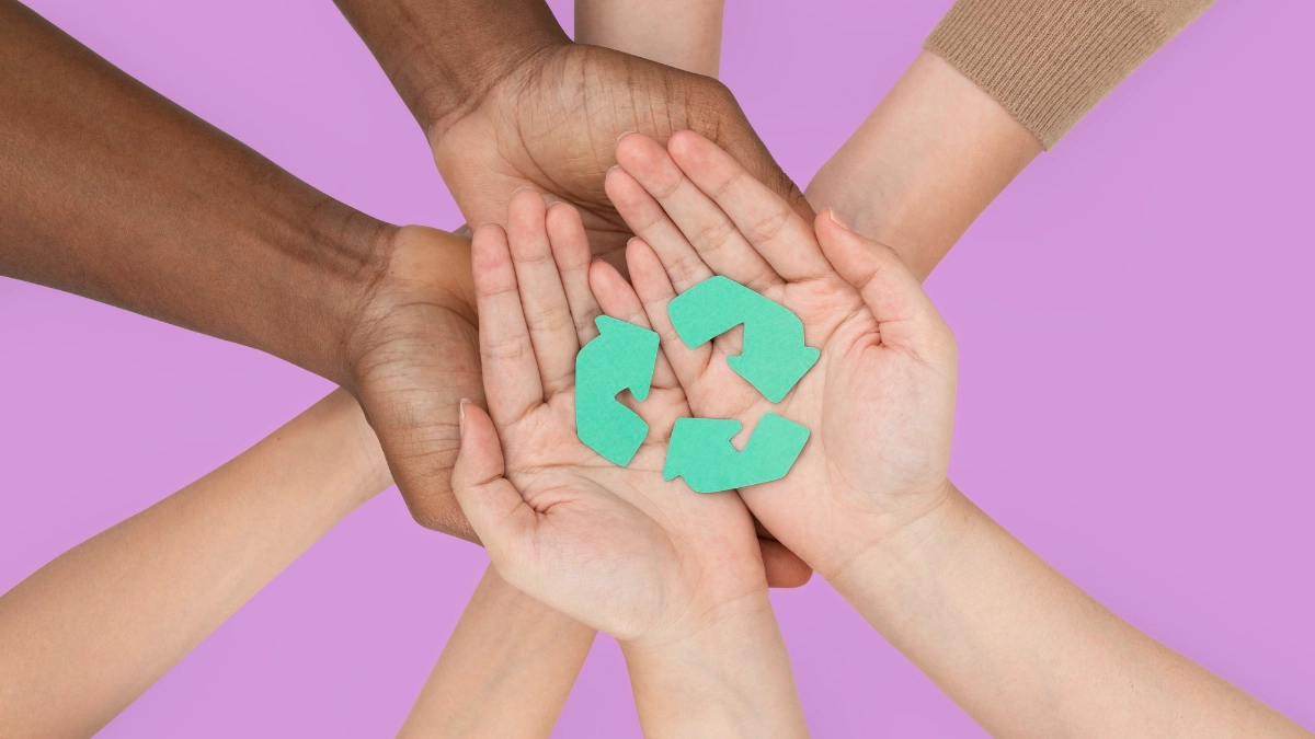 A group of hands holding recycling symbols